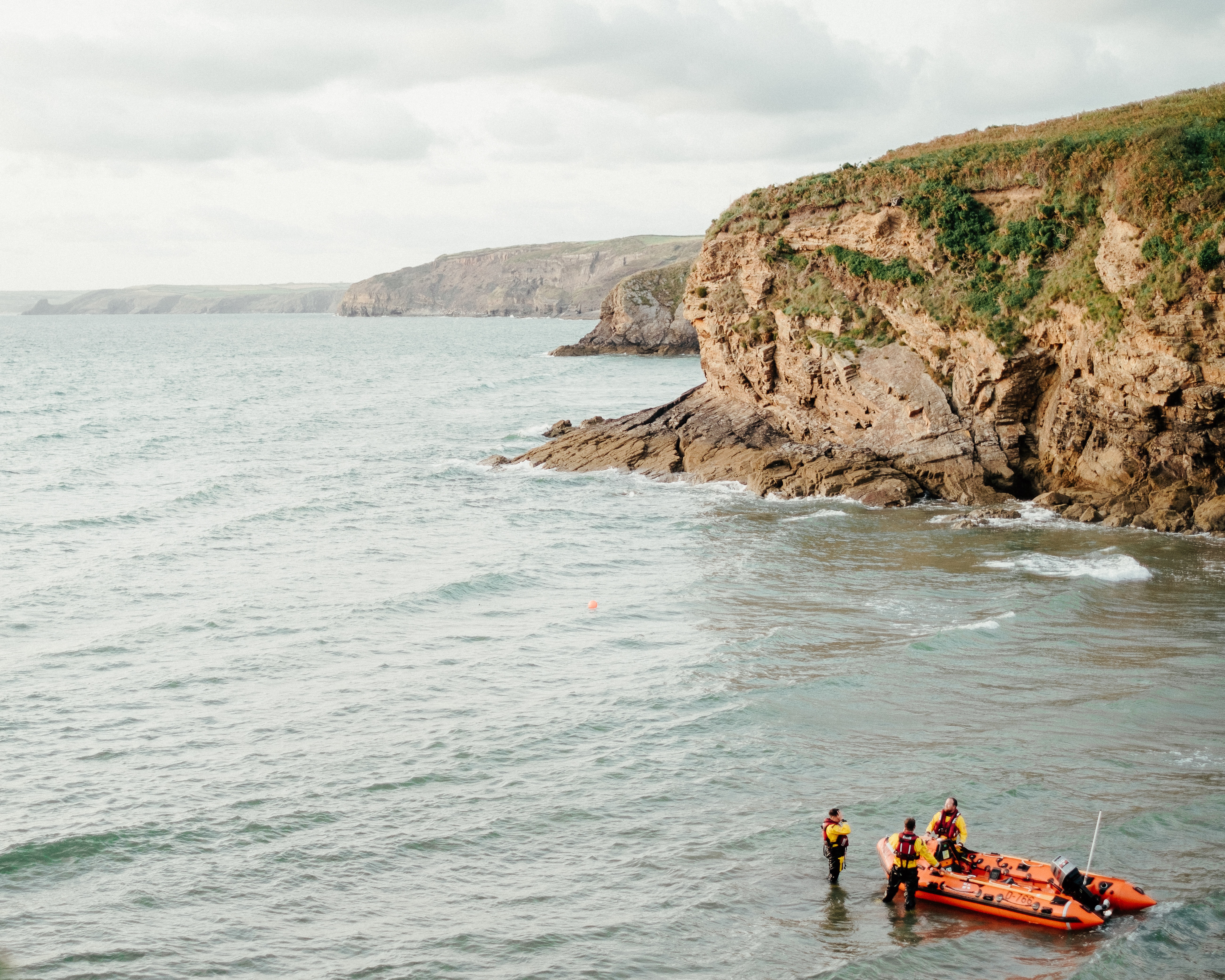 Photo by Harry Cooke: https://www.pexels.com/photo/anonymous-rescuers-standing-in-sea-near-boat-against-overcast-sky-6194845/